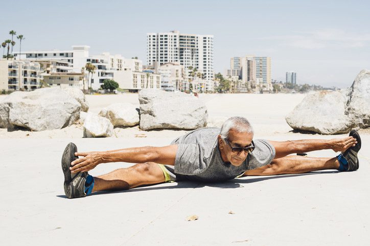 Senior man, exercising on beach, stretching, Long Beach, California, USA
