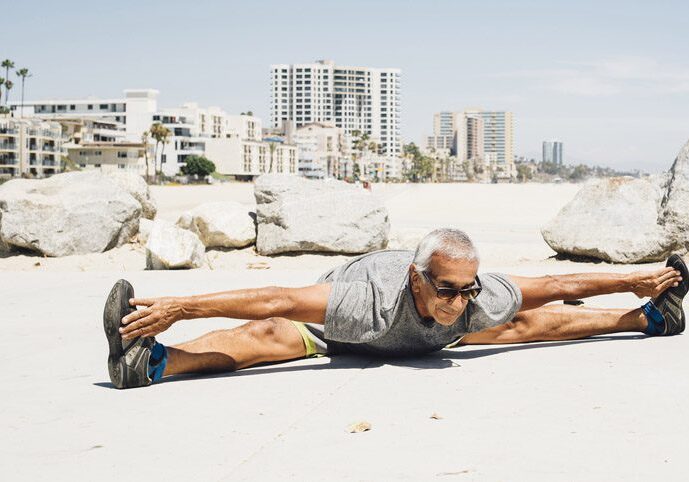 Senior man, exercising on beach, stretching, Long Beach, California, USA